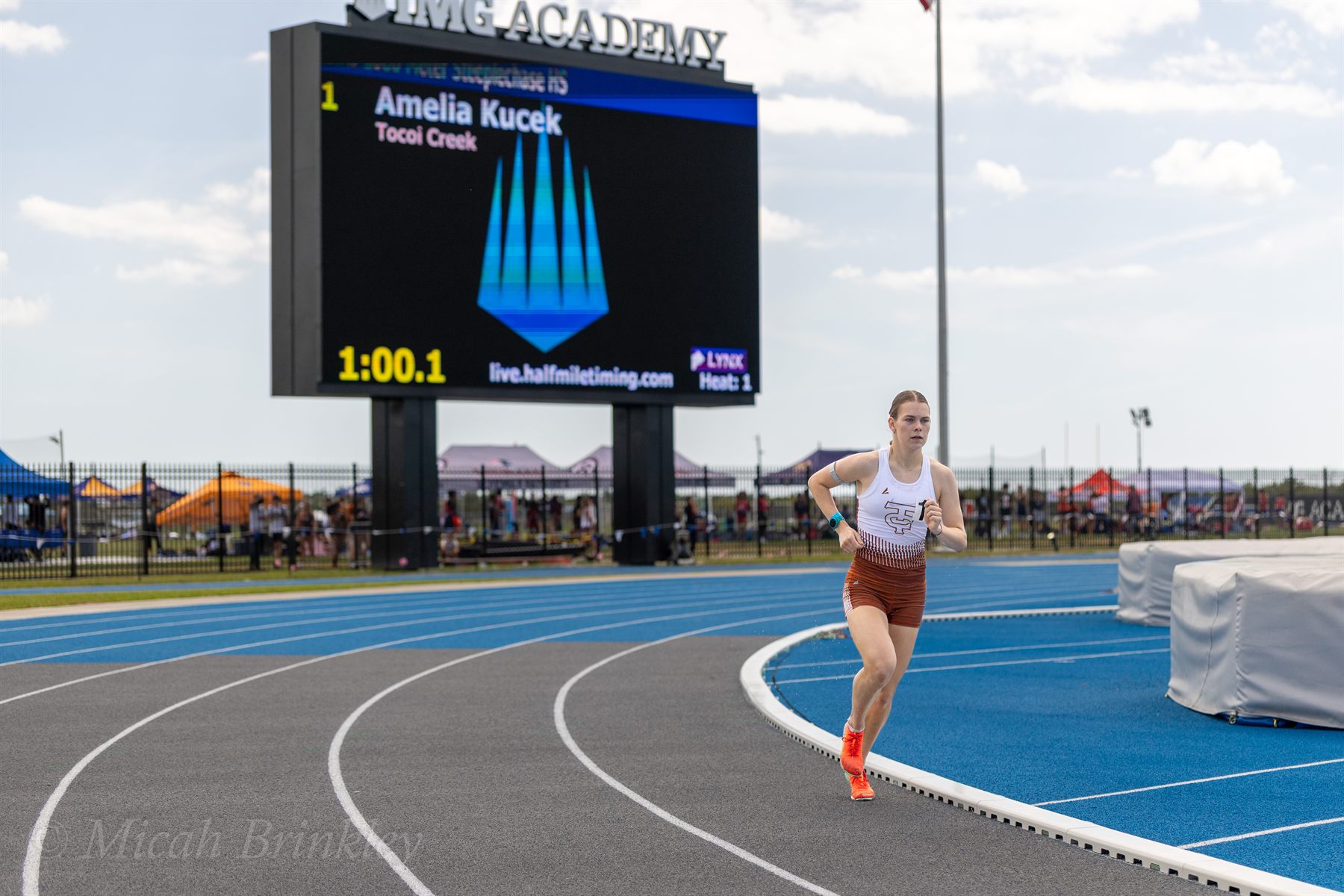 Amelia Kucek racing at IMG Academy, her name on the stadium scoreboard